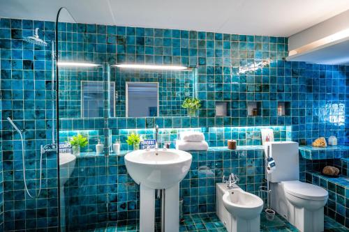 谢瓦布朗克Domaine de Valloncourt的蓝色瓷砖浴室设有水槽和卫生间
