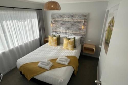 拉塞尔Stay n Play n Russell的卧室配有一张带黄色枕头的大型白色床。