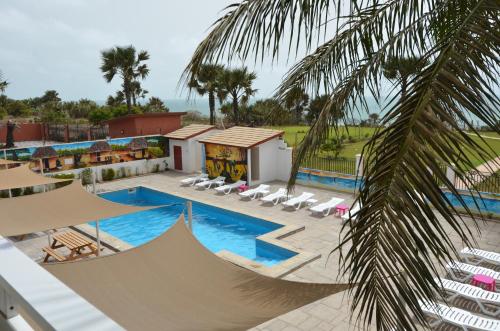 Brufut海洋别墅高地酒店的一个带游泳池、椅子和棕榈树的度假村