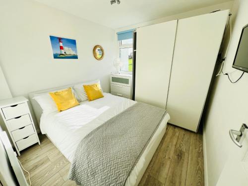 桑当2 Bedroom Chalet SB22, Sandown Bay, Isle of Wight, Dog Friendly的一间小卧室,配有一张带黄色枕头的床
