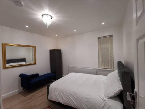 卢顿Three Bedroom Modern Apartment by Luton Airport and Luton Station的卧室配有白色的床和蓝色椅子