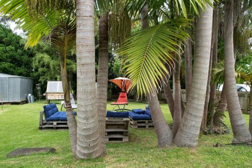 凯塔亚Huriana Place的棕榈树之间的庭院配有椅子和遮阳伞