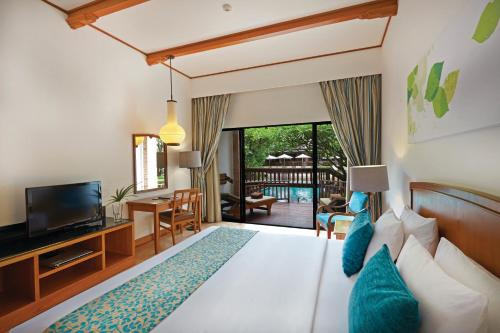 北芭堤雅兀兰酒店芭堤雅度假村的一间卧室配有一张床和一台电视,还设有一间客厅