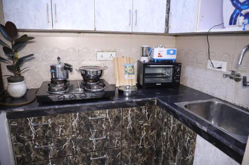 新德里divine India Service Apartment 1Bhk,L-36B,Saket的厨房配有水槽、炉灶和微波炉