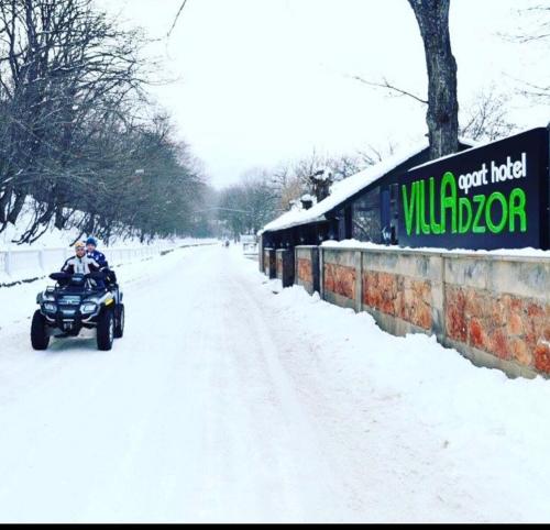 萨克德佐尔镇Villadzor Apart Hotel的骑四轮摩托车沿着雪覆盖的道路行驶的人
