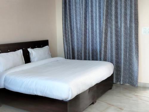 比尔瓦BIR HOTEL的一张带白色床单和蓝色窗帘的床