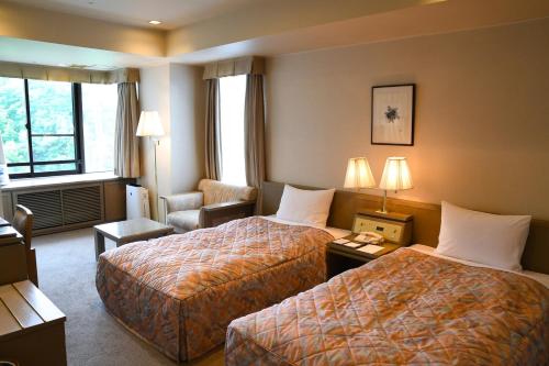 嬬恋村Karuizawakurabu Hotel 1130 Hewitt Resort的酒店客房,配有两张床和椅子