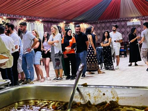 亚喀巴wadi rum guest house camp的一群人站在桌子旁吃食物