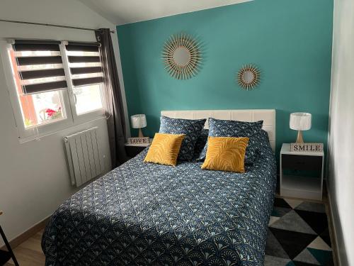 Sainte-Croix-en-PlaineMaison « jardin la cigogne »的一间卧室配有一张带蓝色墙壁和黄色枕头的床