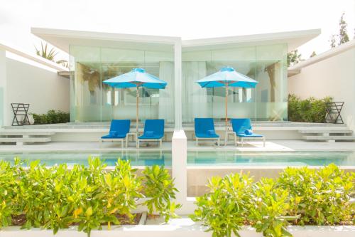 湄南海滩Explorar Koh Samui - Adults Only Resort and Spa的一个带蓝色椅子和遮阳伞的游泳池