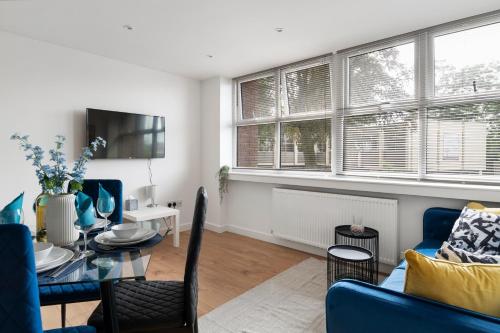 BuckinghamshireLivestay-Modern Apartments Building in Aylesbury的客厅配有桌子和蓝色沙发