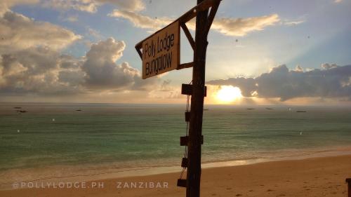 吉汶瓦Polly Lodge Bungalow Zanzibar Kiwengwa的海滩上的一个街道标志,背着太阳