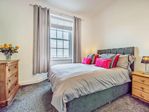Allonby1 Bed in Allonby SZ356的一间卧室配有带粉红色枕头的床和窗户。