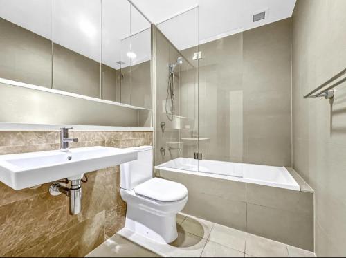 悉尼Cozy stylish home in Rhodes的浴室配有盥洗盆、卫生间和浴缸。