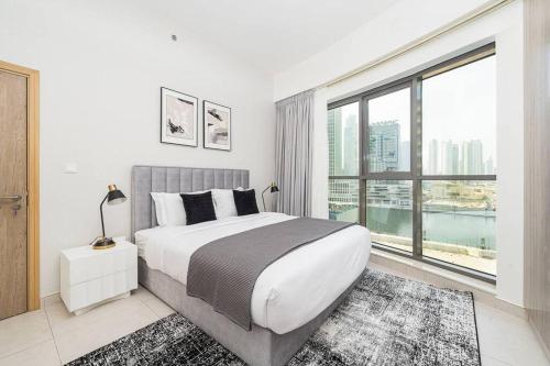 迪拜Manzil - 1BR in The Bay with Canal View nr Dubai Mall的一间卧室设有一张大床和一个大窗户