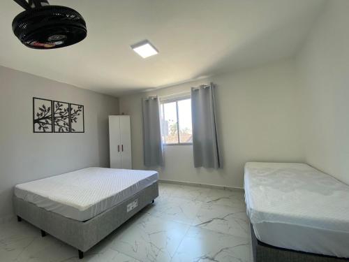 巴拉那州蓬塔尔Apartamento 1 quadra do mar的一间卧室设有两张床和窗户。