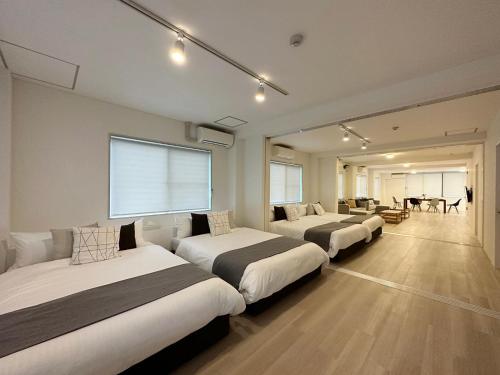 廿日市bHOTEL Kaniwasou 201 2BR Apt, Near Itsukushima Shrine, For 12 Ppl的酒店客房设有三张床和一张桌子