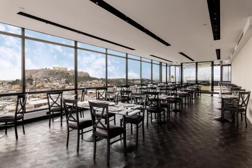 雅典Astor Hotel Athens的用餐室配有桌椅和大窗户