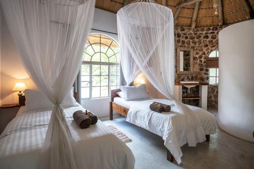 MamonoMobola Lodge的卧室配有2张带白色窗帘的床