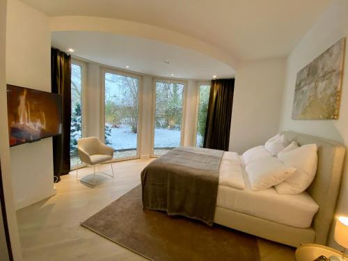 北施泰门Luxuriöse Villa nahe Messe, zwischen Hannover und Hildesheim的一间卧室配有一张床、一把椅子和窗户。