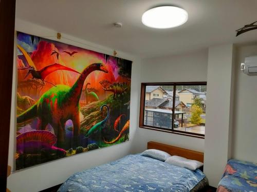 胜山市11月フルリフォーム 12月オープン恐竜一色ゲストハウスDinosaur Guesthouse的卧室的墙上挂有恐龙画