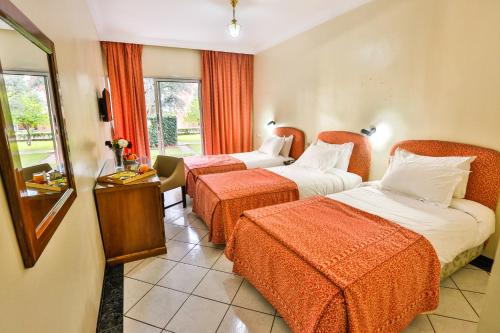 贝尼迈拉勒Complexe El Bassatine的酒店客房带两张带橙色床单的床