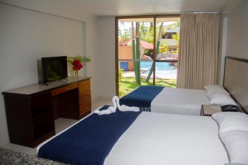 波拉马尔Hotel Margarita Dynasty的一间卧室设有两张床、一台电视和一扇窗户。