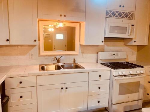 塞金Elm Street Cottage的厨房配有白色橱柜、水槽和炉灶。