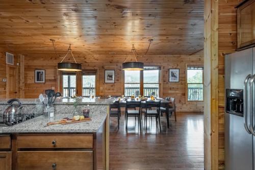 加特林堡Hickory Ridge by AvantStay Incredible Private Elevated Cabin Sleeps 20的厨房以及带桌椅的用餐室。