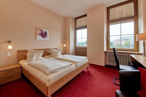贝尔恩卡斯特尔-库斯Moselhotel Römischer Kaiser的酒店客房设有一张床、一张书桌和窗户。