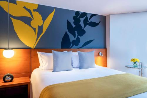 波哥大Avani Royal Zona T Bogotá Hotel (previously NH Bogotá Boheme Royal)的一间卧室配有一张蓝色和黄色墙壁的床