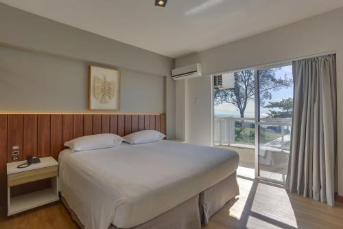 弗洛里亚诺波利斯波尔图索尔海滩酒店的一间卧室设有一张大床和一个大窗户