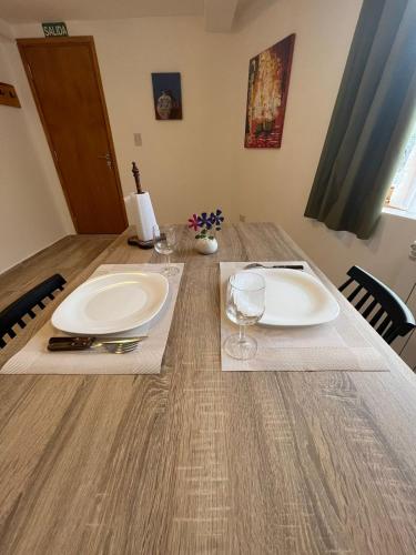 乌斯怀亚Ushuaia_aparts Depto 1的一张木桌,配有两个白板和酒杯