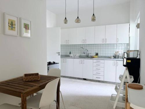 贝鲁特Sunny Eclectic 3BR house in Gemmayze的厨房配有白色橱柜和木桌