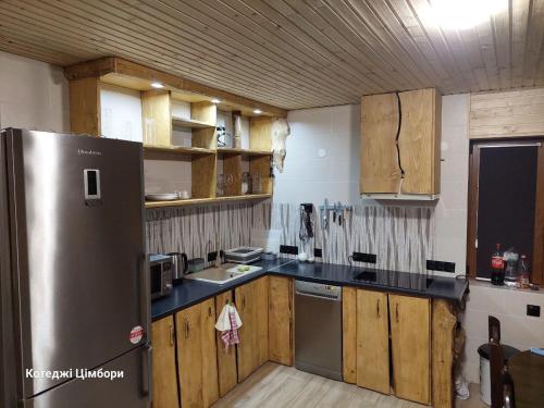 亚布卢尼齐亚Котеджі Цімбори的厨房配有木制橱柜和不锈钢冰箱。