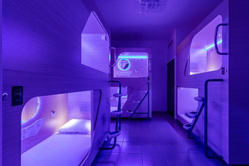 迪拜Berloga Capsule JBR的紫色客房,配有一张床和两张凳子