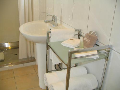 哈士汀弗雷姆勒汽车旅馆 的浴室配有水槽、玻璃桌和毛巾