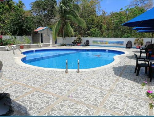 普罗维登西亚HOTEL POSADA DEL MAR的庭院内的游泳池配有桌子和遮阳伞