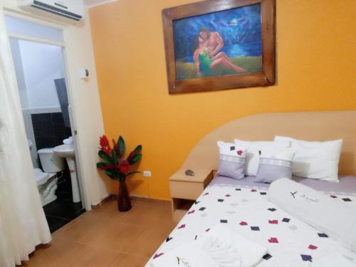 马尔多纳多港Hotel Botón de Oro的卧室配有一张床,墙上挂有绘画作品