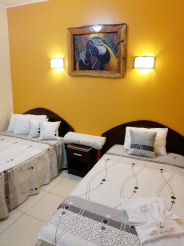 马尔多纳多港Hotel Botón de Oro的一间设有两张床的客房,墙上挂着一幅画