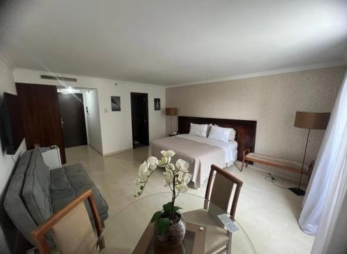 巴西利亚Brasil 21 suite flat的酒店客房配有一张床和一张沙发桌子
