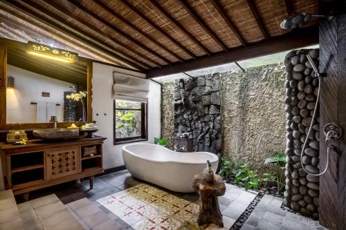 乌布Pramana Watu Kurung的带浴缸和石墙的浴室