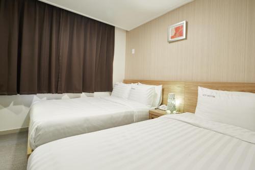 首尔Top Hotel & Residence的酒店客房设有两张床和窗户。