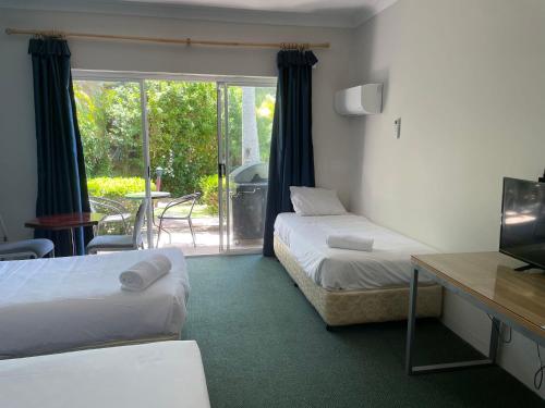瓦布利尔Seaside Garden Retreat Accommodation的酒店客房设有两张床和电视。