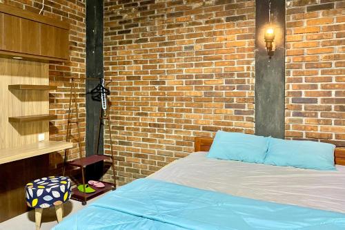 SoprayanTwoSpaces Living at Pondok Pakde, Jogja的一间卧室设有砖墙和一张床