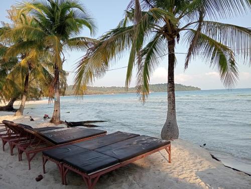 Phumĭ Kâoh RŏngWhite Pearl Beach的海滩上的一组桌子和棕榈树
