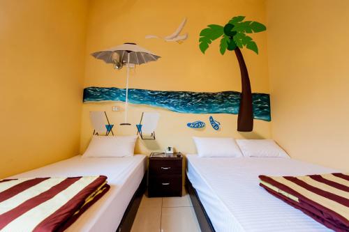 绿岛诺亚民宿的墙上有一棵棕榈树的房间里,有两张床