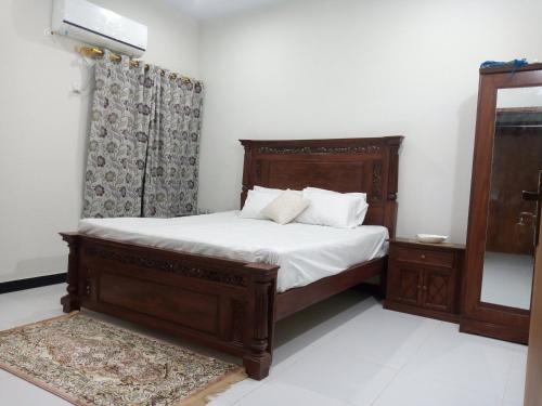 卡拉奇Nursery Inn的一间卧室配有一张带白色床单和枕头的木制床。