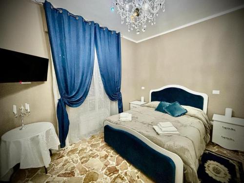 罗塔迪马尼亚Il Castello Di Venere的一间卧室配有一张带蓝色窗帘和吊灯的床。