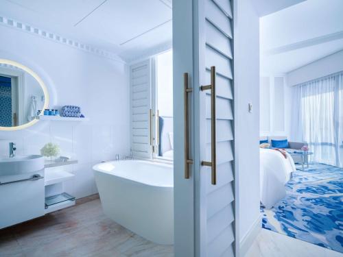 迪拜索菲特迪拜朱美拉海滩酒店的白色的浴室设有浴缸和床。
